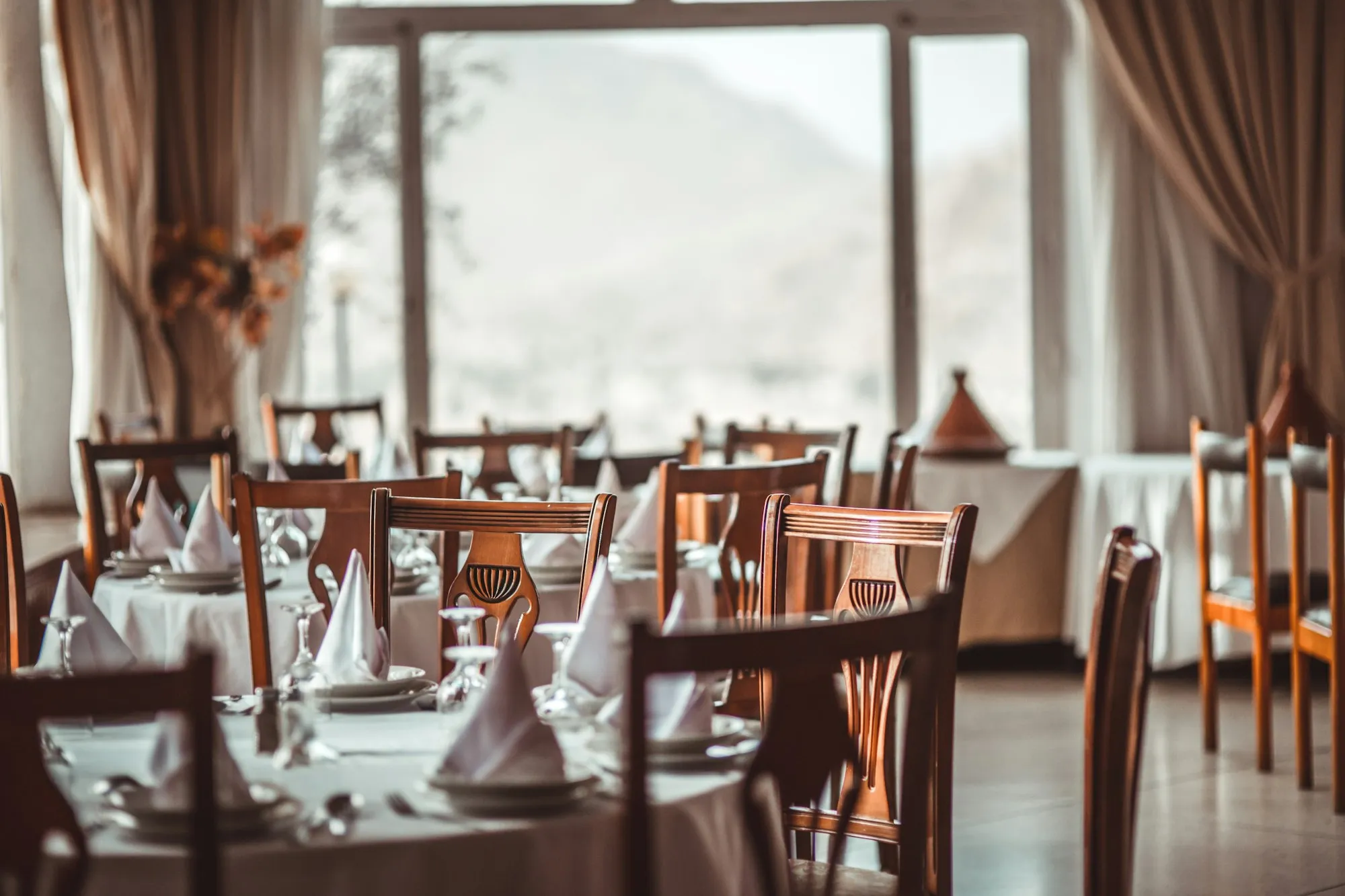 Dimly lit restaurant dining room with set tables